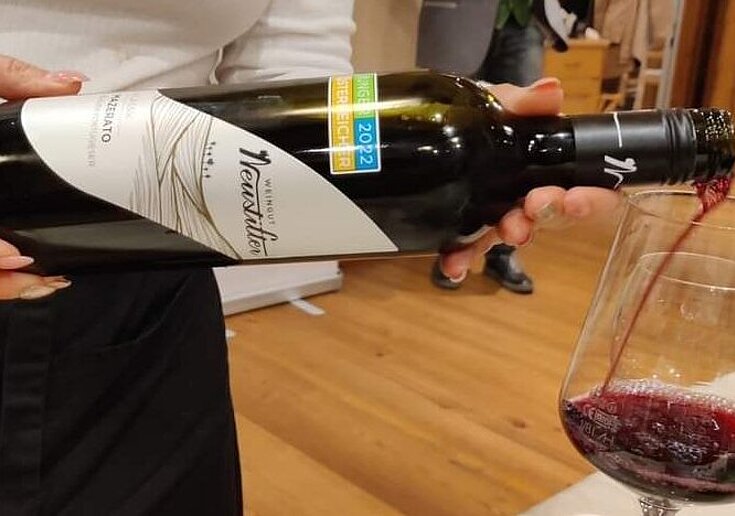 Ein Servicemitarbeiter schenkt einem Gast ein Glas Jungwein ein. Es handelt sich dabei um einen Mazerato.