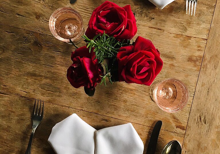 Romantisch gedeckter Tisch mit Rosen und herzförmigen Servietten.