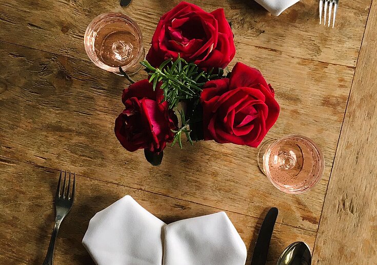 Romantisch gedeckter Tisch mit Rosen und herzförmigen Servietten.