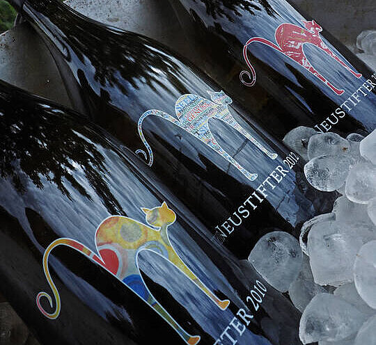 Drei Stockkultur Weinflaschen liegen in einem Weinkühler auf Eiswürfeln.