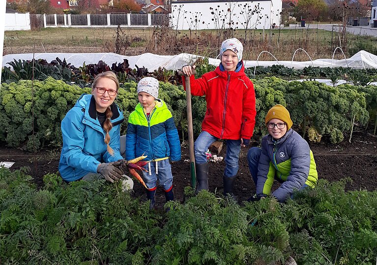 Frau Ingrova posiert mit ihren Kindern im Gemüsegarten.