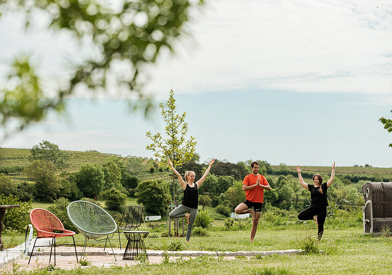 Drei Personen, die im Garten vom Wein.Hotel Neustifter Yoga machen