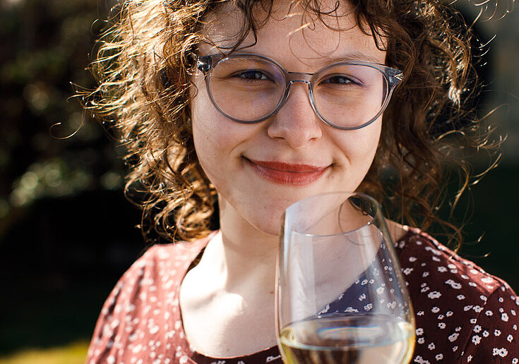 Die Nahaufnahme zeigt Laura Neustifter mit einem Glas Weißwein.