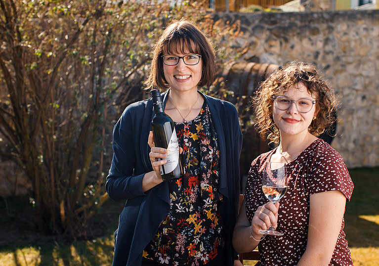 Monika und Laura Neustifter mit einer Flasche Neustifter Wein und einem Weinnglas