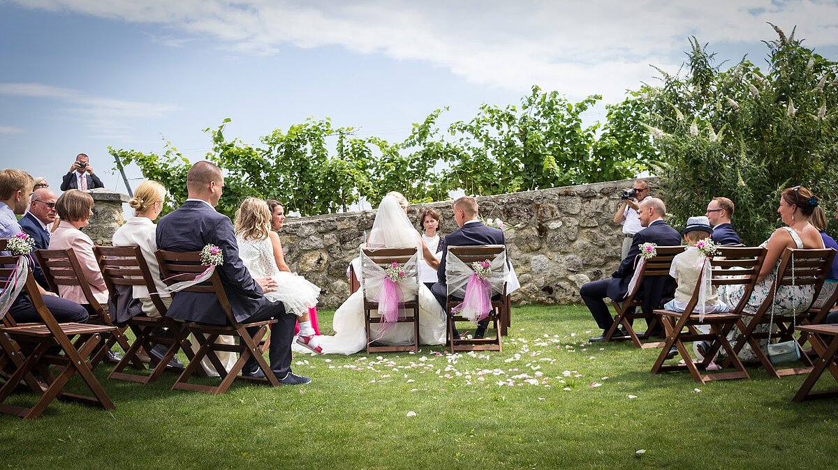 Im Garten vom Wein.Gut Neustifter feiert ein Brautpaar ihre standesamtliche Hochzeit mit dutzenden Gästen.