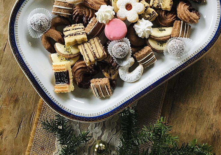 There are all kinds of Christmas cookies on a white plate.