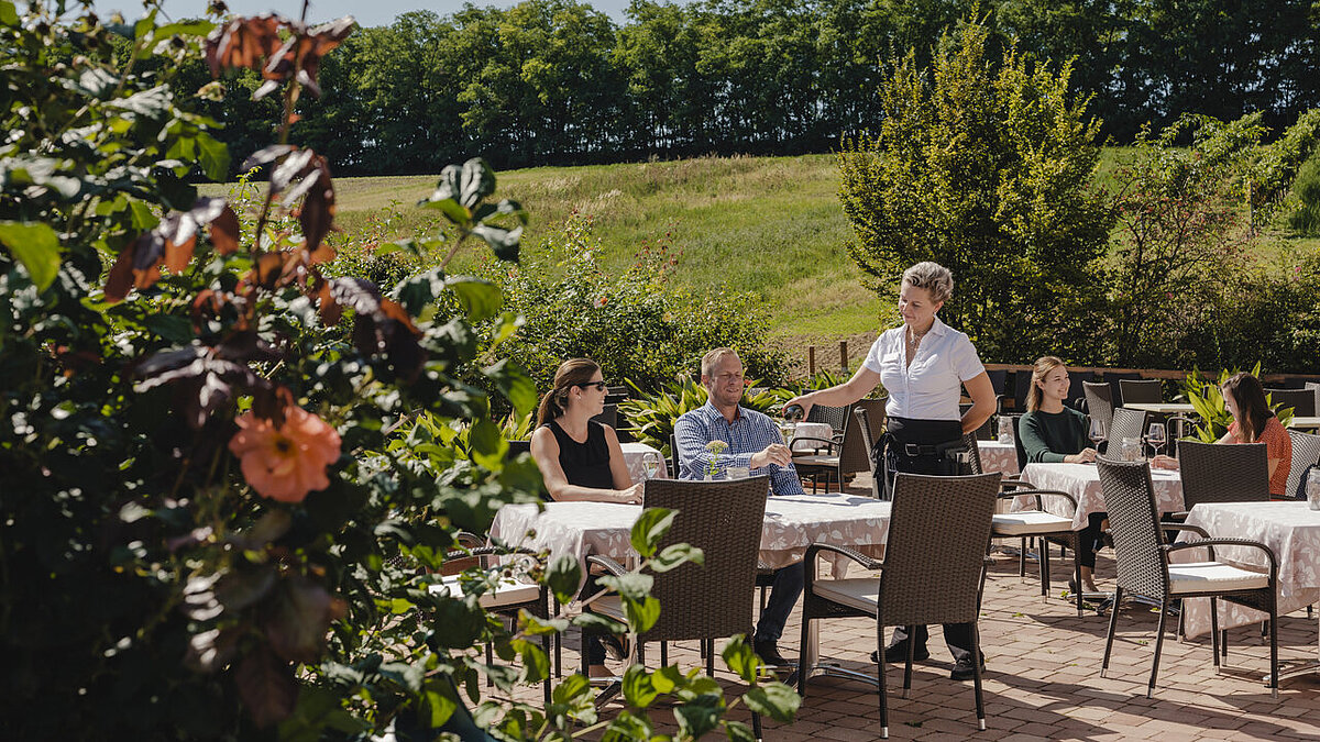 Auf der Weingartenterrasse bedient eine Kellnerin die Gäste.