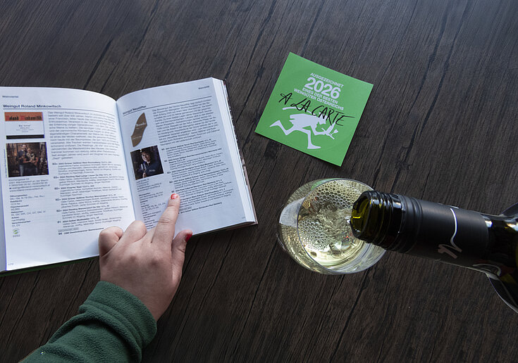 A la Carte Wine Guide 2026 with a glass of wine and a bottle of Neustift wine