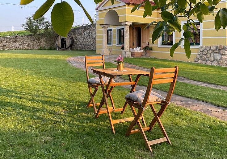 Ein kleiner Tisch mit zwei Stühlen steht im Gastgarten der TOP Heuriger Wein.Küche.