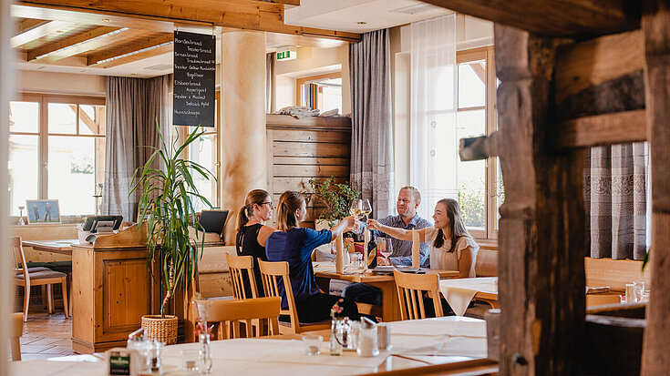 Auf einem Tisch in der Gaststube vom Wein.Restaurant Neustifter sitzt eine Familie und genießt ihr Essen.